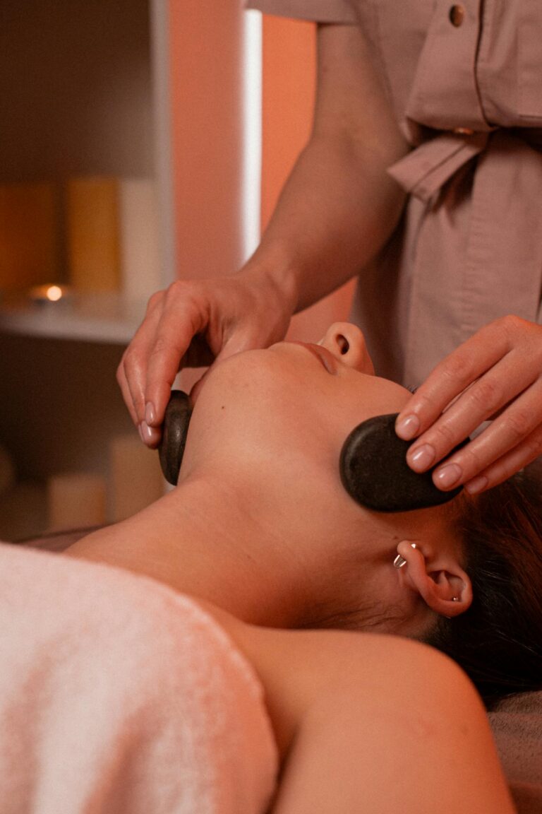 Relaxing stone massage on woman's face in a calm spa environment. facial Durbanville at home
