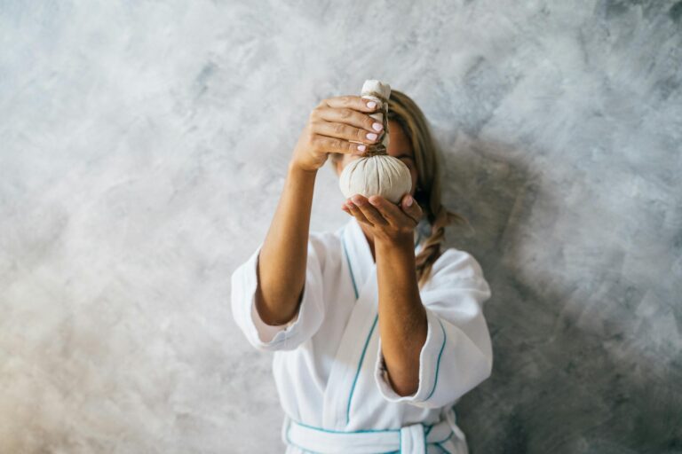 Woman in spa robe holding herbal compress for a rejuvenating spa treatment. private spa Cape Town